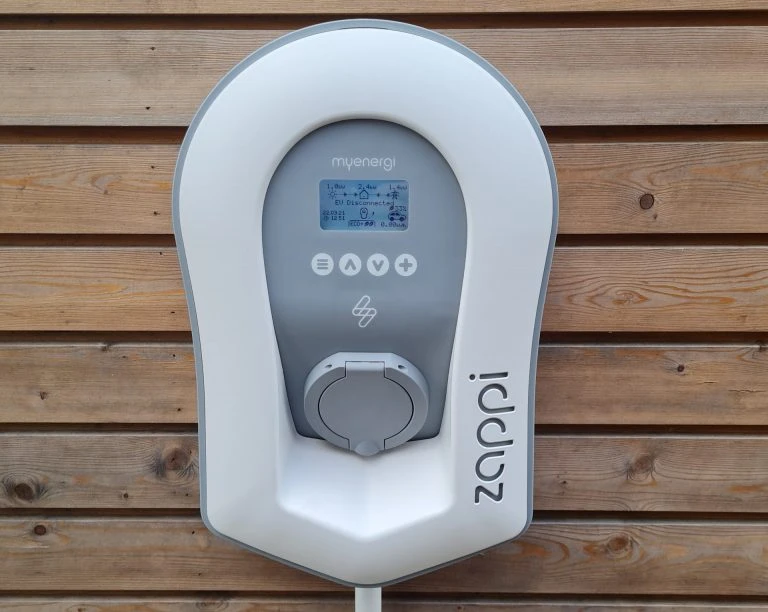white EV charger socket installed on timbe building