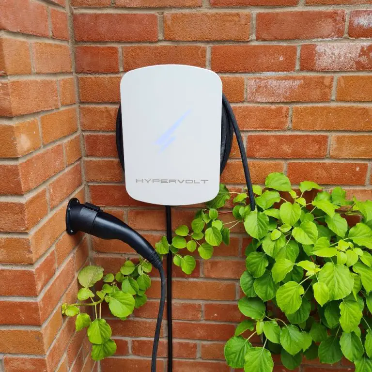 White Hypervolt EV charger with tethered lead wrapped around unit, on brick wall.