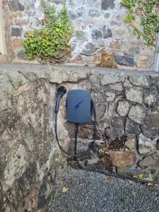 Grey tethered EV charge point on stone wall