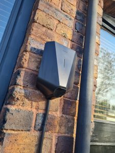 black EV charger on brick wall