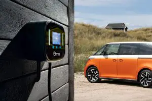 Ohme charge point on wall with orange VW ID Buzz on driveway